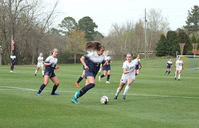 Marist School defensive back Eva Wirtz (#5), left center, gets a beat on the ball so she can out maneuver St. Pius X midfielder Ingrid Capone, right center. Photo By Michael Alexander