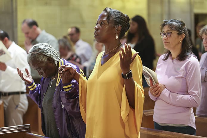 (L-r) Norma Sonier from Christ Our Hope Church, Lithonia, her daughter Peggy Ballou from Basilica of the Sacred Heart of Jesus, Atlanta, and Sonia Garcia Lopez from Our Lady of the Annunciation Church, Albuquerque, New Mexico, stand for the praying of the Our Father during the Mass of Reparation at the Cathedral of Christ the King, Atlanta. Photo By Michael Alexander