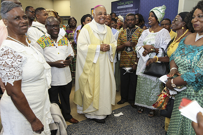 Archbishop Wilton D. Gregory, center, smiles as a contingent from the Ghanaian Catholic Community sing “Aseda nyinaa yε Wodze,” which literally means “All Praise and Thanks to God.” The singing took place as they greeted Archbishop Gregory after the farewell Mass. Photo By Michael Alexander