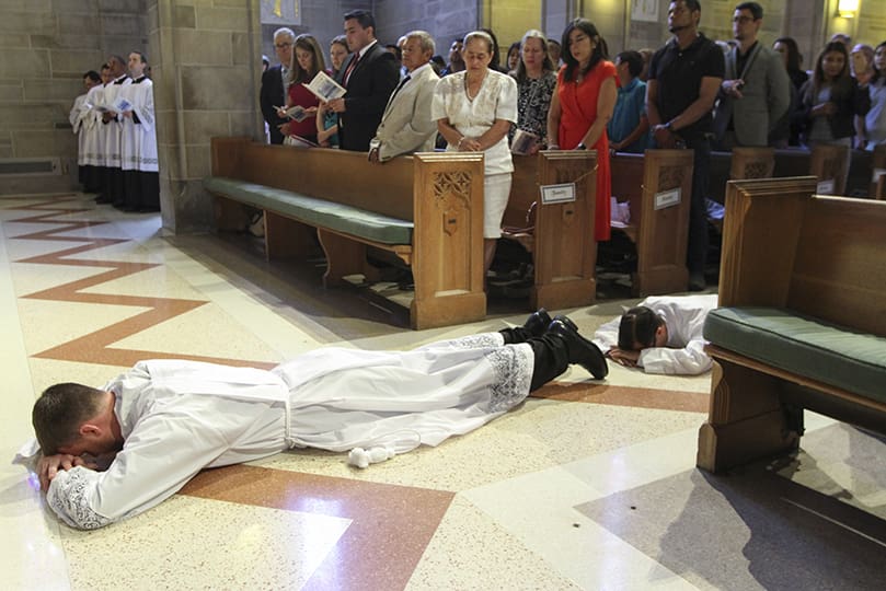 Two of the three transitional diaconate ordination candidates, (l-r) Paul Porter and Miller Gómez Ruiz, lie prostrate in the center aisle at the Cathedral of Christ the King, Atlanta. They were ordained to the transitional diaconate with Cristian Cossio on May 25. Photo By Michael Alexander