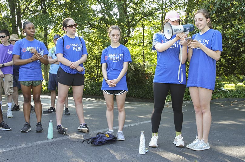 On the first stop after one mile of walking, Marist School sophomore Sara Jane Shulman holds the megaphone as her classmate, Abby Testani, as she reads a poem she wrote and titled 