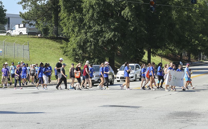 The walkers cross East Ponce de Leon Avenue at the intersection of Dekalb Industrial Way, as they make their way to the Dekalb Farmers Market, the second mile of their five-mile journey. Photo By Michael Alexander