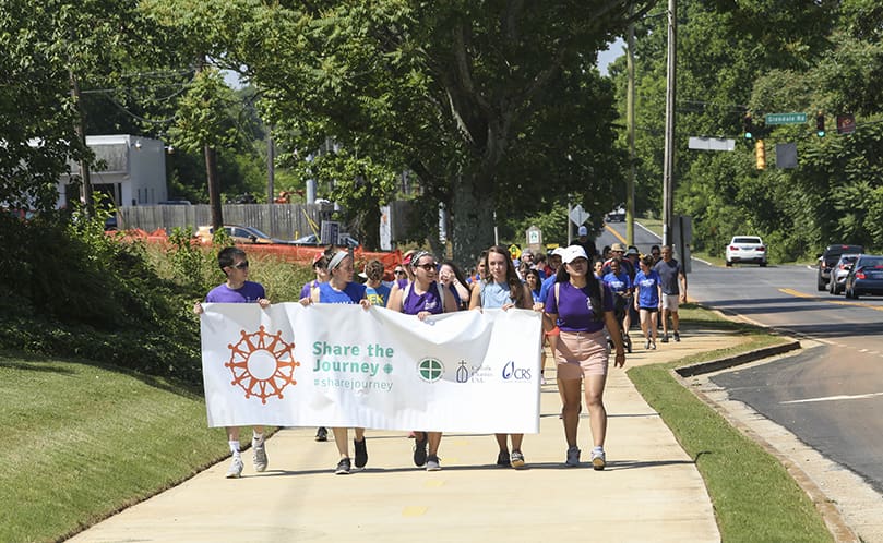 Carrying the Share the Journey banner as they approach the four-mile point are (l-r) Jimmy Lai, Emma Dunphy, Adrian Laudani, Emily Longino and Grace Lin. All four serve in some capacity at Catholic Charities Atlanta. Lai and Lin are AmeriCorps volunteers with Refugee Services. Dunphy is a paralegal with Immigration Legal Services. Laudani is a Jesuit volunteer working as a refugee resettlement specialist. Longino is a volunteer. Photo By Michael Alexander