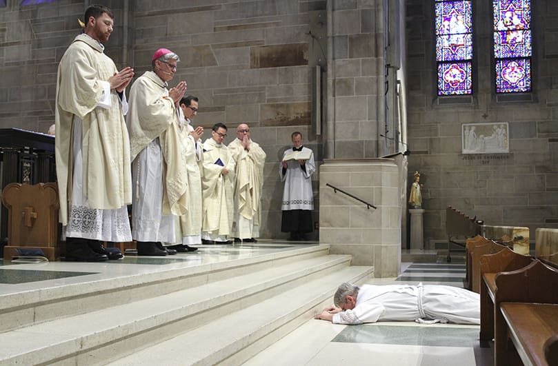 Priesthood ordination candidate Mark White is prostrated before the altar at the Cathedral of Christ the King, Atlanta, during the invitation to prayer. Bishop Bernard E. Shlesinger III, top step, second from left, was the principal celebrant and homilist for the June 1 ordination. Photo By Michael Alexander