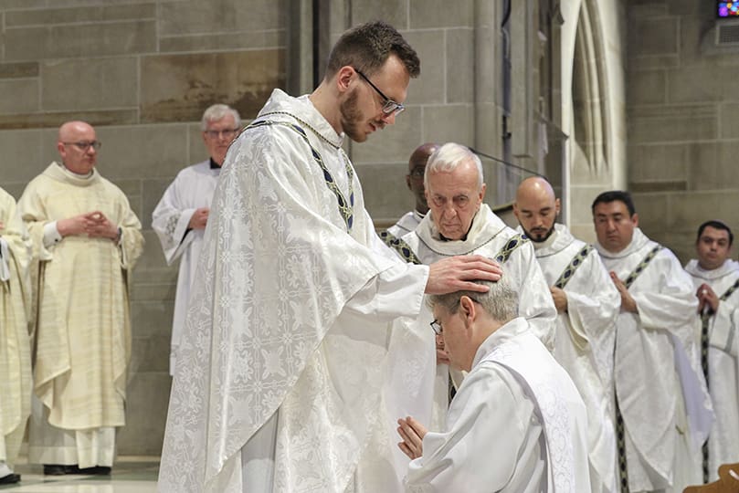 Father Michael Bremer, parochial vicar at St. Brigid Church, Johns Creek, lays hands upon ordination candidate Mark White during his ordination to the priesthood. Father Bremer was ordained a priest in 2018. Photo By Michael Alexander