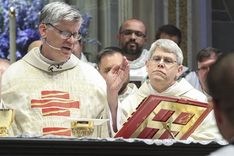 Father Mark White, right, stands at the altar with his brother clergy during the Liturgy of the Eucharist, as Bishop Bernard E. Shlesinger III, left, the principal celebrant, recites a prayer. Photo By Michael Alexander