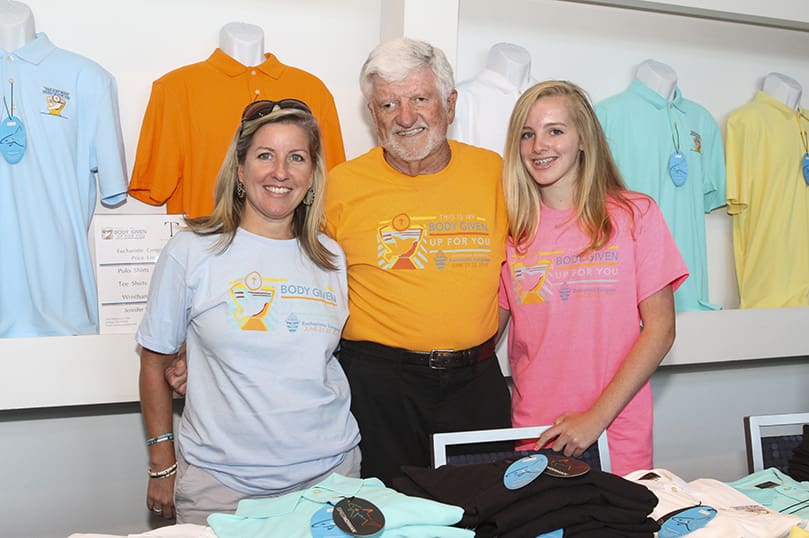 Tom Carroll, center, his daughter Jennifer Rollauer, left, and his 13-year-old granddaughter Kate represent three generations of T-shirt vendors at the Eucharistic Congress. Carrollâs company, TC Marketing, has been selling shirts at the annual event for over a decade. Recently diagnosed with Lymphoma, Carroll didnât want to miss this yearâs event as he prepares for cancer treatment.  Photo By Michael Alexander