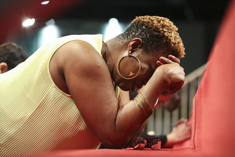 During the June 21 healing service, Carol Ugonna removes her tear-smeared eyeglasses as she prays with fervor on the steps leading up to the altar, where the Blessed Sacrament is exposed. Ugonna attends St. Theresa of the Child Jesus Church in Douglasville. Photo By Michael Alexander