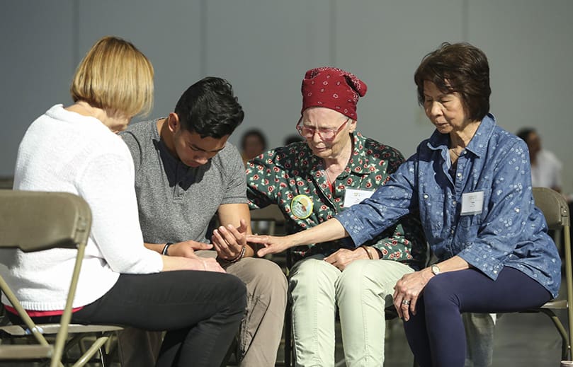 After the healing service, (r-l) Rose Brual of St. George Village, Roswell, Catharine Monet of St. Peter Chanel Church, Roswell, and Kathy Bryan, far left, from Church of St. Ann, Marietta, hang around to pray with families and individuals like Mario Flamenco, second from left, of St. Lawrence Church, Lawrenceville. The women are members of Resurrected Life, a healing prayer ministry. Photo By Michael Alexander