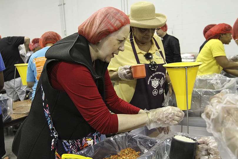 Alix Shattuck of St. Jude the Apostle Church, Sandy Springs, foreground, and Tracy Harper of Most Blessed Sacrament Church, Atlanta, background, work with others as part of the meal packing team during session one of Starve Wars. Shattuck, a United States Army veteran, answered the call for veterans and active duty military to support the 2019 Eucharistic Congressâ Starve Wars. Photo By Michael Alexander