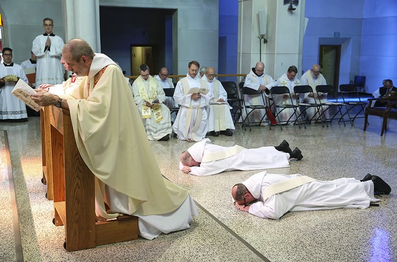 Trappist monks and ordination candidates to the priesthood, (foreground to background) Brother Peter Damian and Brother Cassian Russell, prostrate themselves before the altar during the Litany of Saints. Photo By Michael Alexander