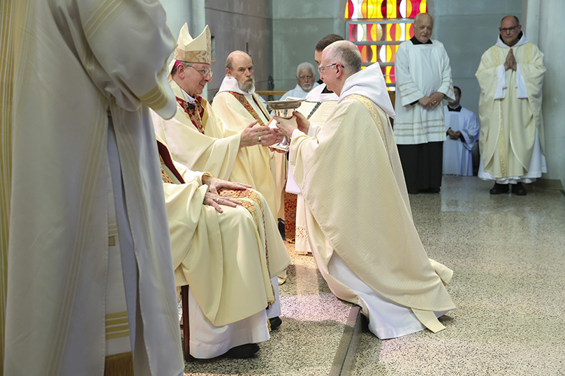 After the prayer of ordination, Bishop Joel M. Konzen, SM, presents the paten and chalice to Father Cassian Russell, OCSO, as Father Peter Damian, OCSO, background, far right, waits his turn. Photo By Michael Alexander
