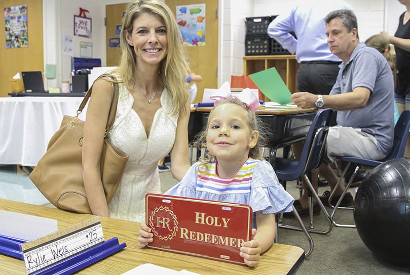 Seated next to her mother, Tammy, in her kindergarten classroom, Ava Welles, a new student at Holy Redeemer School, Johns Creek, proudly shows off the school license plate that will likely go on her mother’s vehicle. Photo By Michael Alexander