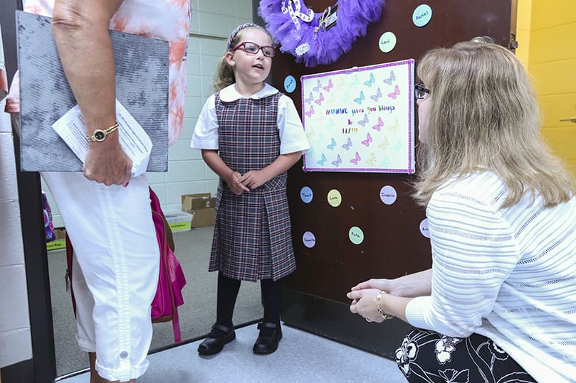 On the first day of school, August 5, at St. John Neumann Regional School, Lilburn, five-year-old Aurora Wyatt, center, formally introduces herself to her kindergarten teacher, Nicole Roemer, right. Wyatt and Roemer share something in common. They’re both new to St. John Neumann for the 2019-2020 school year. Photo By Michael Alexander