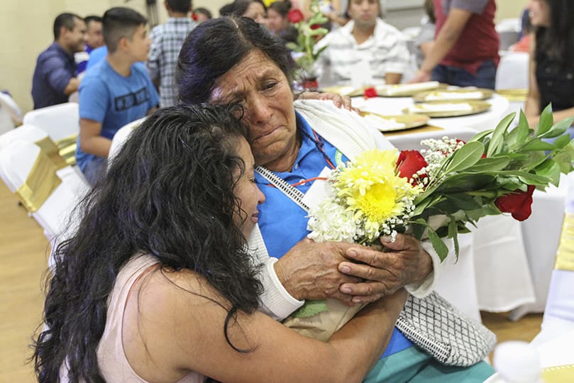 Even after their initial encounter when Maria Monroy, left, presented her 73-year-old mother, Juana Cruz, with a bouquet of flowers, Monroy continued an extended embrace with her mother at the table. Their last face-to-face was in 2001. Photo By Michael Alexander