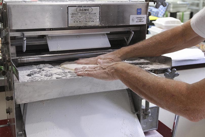 Nick de la Torre places some dough in the dough rolling machine. Photo By Michael Alexander