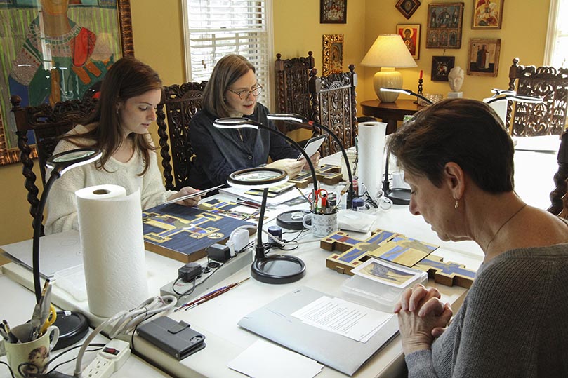 Nancy Ewing, middle, started an icon painting class at her northwest Atlanta home in 2017. Today she conducts an afternoon and evening class on Tuesdays. Before the painting begins, she prays with early arrivals for the afternoon class. They include students and Holy Spirit Church parishioners Rachel Grantham, left, and Mari Hobgood. Photo By Michael Alexander