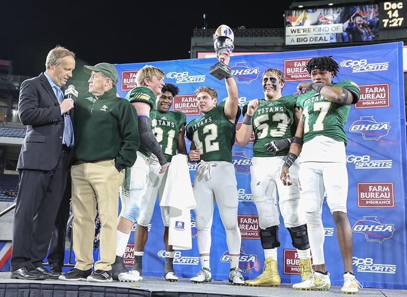 Following the team's state championship victory over Oconee County, emotions ran high among Blessed Trinity High School football players as head coach Tim McFarlin, second from left, is interviewed by Georgia Public Broadcastingâs Jon Nelson. The senior captains celebrating with the championship trophy are (l-r) Ryan Attaway, Elijah Green, Nate Matthews, Jackson Filipowicz and Quinton Reese. Photo By Michael Alexander