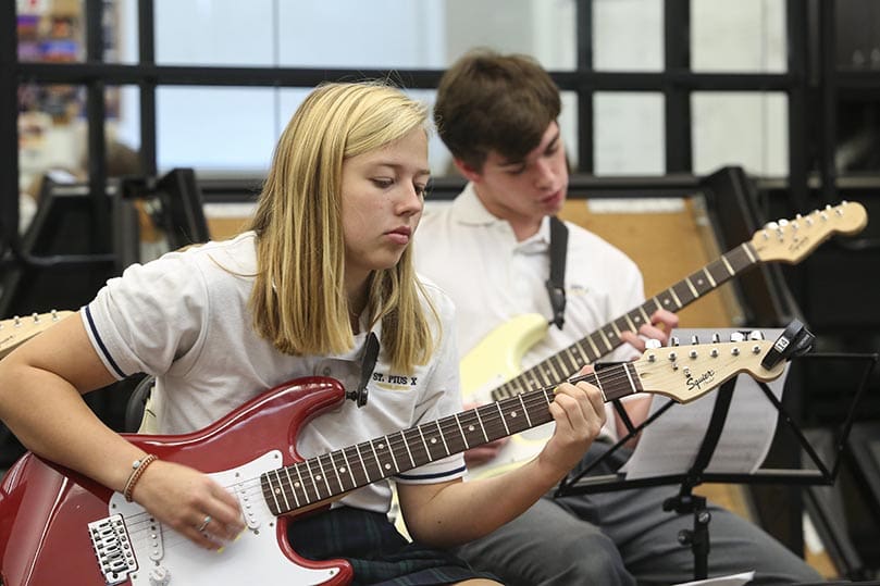 St. Pius X High School senior Amelia Temme and junior Benjamin Whitaker, background, rehearse for an upcoming performance in their advanced jazz guitar class. Photo By Michael Alexander