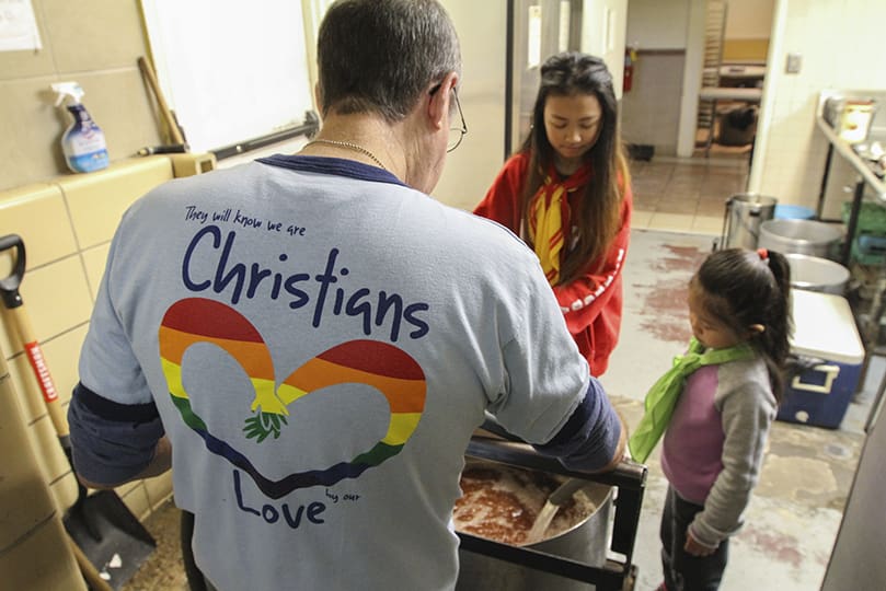 As they prepare tea for the St. Francis Table guests, Bill Emery, back to camera, is assisted by six-year-old Vivian Nguyen, right, and 15-year-old Kimberly Nguyen. The two volunteers are not related, but they both attend Holy Vietnamese Martyrs Church, Norcross. For more than eight years, Emery has come every Saturday to help serve a hot meal to those in need. Photo By Michael Alexander