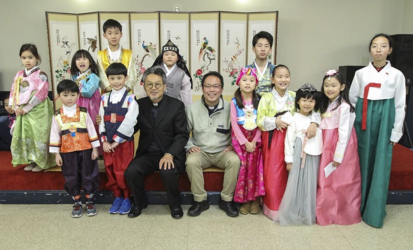 Father Kolbe Man Young Chung, left center, pastor of St. Andrew Kim Church, Duluth, and parochial vicar Father Juchan Kim pose for a photograph with some of the children during a Jan. 26 Lunar New Year celebration at the parish. Photo By Michael Alexander