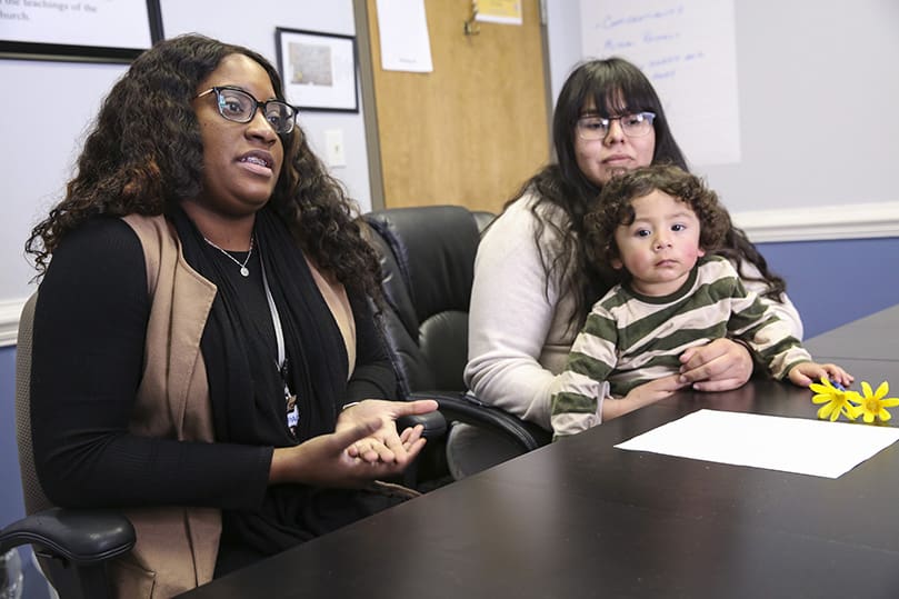 Pregnancy Aid Clinic client advocate Brittany Farmer, left, shares how she convinced Diana Resendiz, right, to seek adoption as an alternative to terminating a recent pregnancy. Resendiz is holding her one-year-old son Alex, one of three children. Photo By Michael Alexander