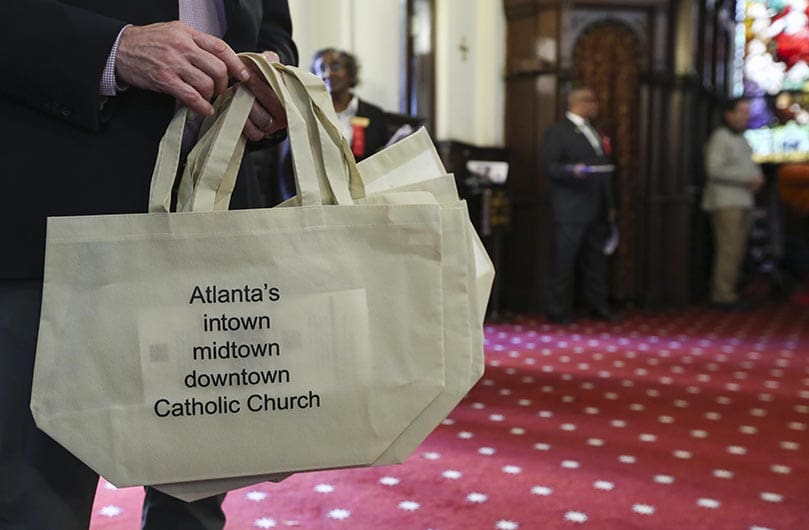 Basilica of the Sacred Heart of Jesus usher Mark Stouffer prepares to hand out gift bags to first time visitors exiting the downtown Atlanta parish after Sunday morning Mass. Photo By Michael Alexander