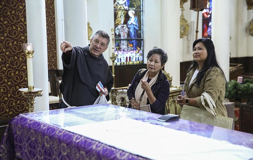 Conventual Franciscan Father John Voytek gives an impromptu tour of the Basilica of the Sacred Heart of Jesus to Iza Perez-Webster, right, and her mother Myrna Perez, center. Here he points to some of the theological symbols on the altar. Iza attends the downtown Atlanta church. Myrna was visiting from Honolulu, Hawaii. Father Voytek resides at Holy Cross Church, Atlanta, but he serves at the Basilica of the Sacred Heart of Jesus. Photo By Michael Alexander