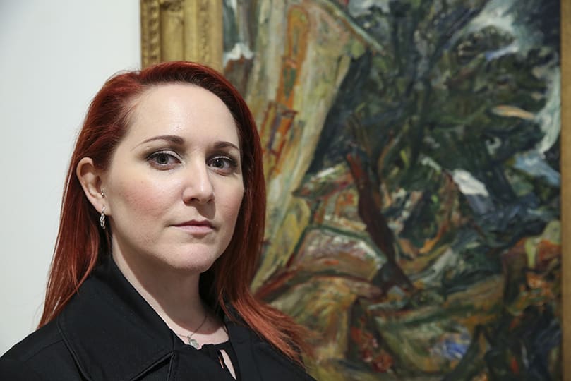 Jayna Hoffacker, program coordinator for the Archdiocese of Atlanta’s Justice and Peace Ministries, stands beside the oil painting done by the late artist, Chaim Soutine, called “Landscape with Figures-Céret.” The painting accompanies the reflection associated with Station Three at the High Museum, Jesus is Condemned by the Sanhedrin. Together Jayna Hoffacker and Father Desmond Drummer envisioned the idea for the Stations of the Cross at the High project. Photo By Michael Alexander