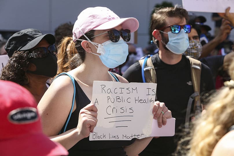A young woman stands in the street during the ure reading, litany and opening prayer that took place prior to the march for racial justice by hundreds of Catholics through downtown Atlanta. Photo By Michael Alexander