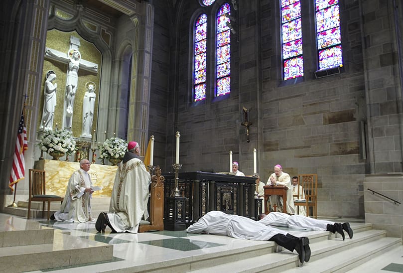 The two transitional diaconate ordination candidates, Robert Cotta and Paul Nacey, lie prostrate on the altar at the Cathedral of Christ the King, Atlanta. Photo By Michael Alexander