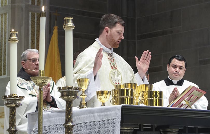 For the first time as a newly ordained priest, Father Paul Porter, center, takes his turn reading a prayer during the Liturgy of the Eucharist. Father Porter’s first assignment will be at St. Peter Chanel Church, Roswell. Photo By Michael Alexander
