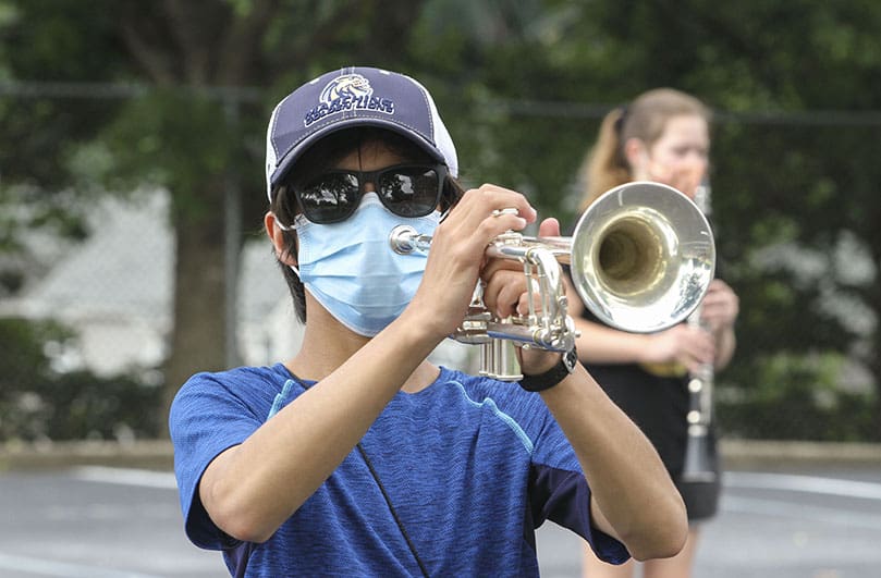 St. Pius X High School trumpet player Ethan Sok, a sophomore member of the Atlanta school's marching band, participates in the sectional practice for brass and wind musicians on the last day of band camp. In addition to the normal outdoor accessories like a cap and sunglasses, masks were worn by musicians this summer to protect fellow students from the potential spread of the coronavirus. Photo By Michael Alexander