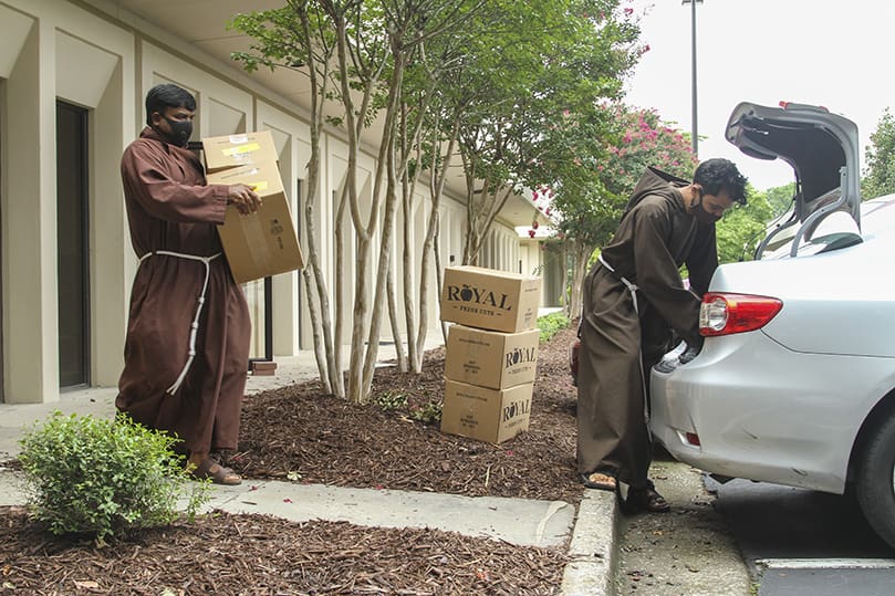 Parked at the Catholic Charities Atlanta office in Tucker, August 14, Brother Praveen Turaka, OFM Cap., left, and Brother Robert Perez, OFM Cap., load boxes of fresh produce into their automobile. They were taking the food to St. Joseph Place, an affordable, independent living retirement community, south of Atlanta. Since their arrival June 23, they have dedicated their efforts to serving poor and marginalized communities. Photo By Michael Alexander