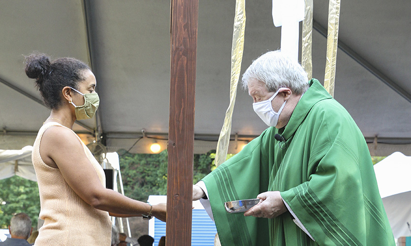 During distribution of the Body of Christ, Chevela Green, left, stands on one side of the communion shield as the main celebrant, Father Paul Berny, stands on the opposite side. Photo By Michael Alexander