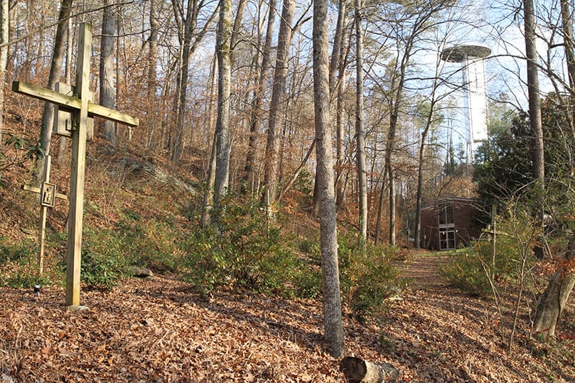 The area below this trail, down along the north ridge to the Chattahoochee River deck and the water’s edge, is where phase five of the Ignatius House work will take place. In the background, up on the hill, is the cell tower and outdoor Montserrat Chapel. Just below that is the retreat house and in the foreground, left, are two Stations of the Cross. Photo By Michael Alexander