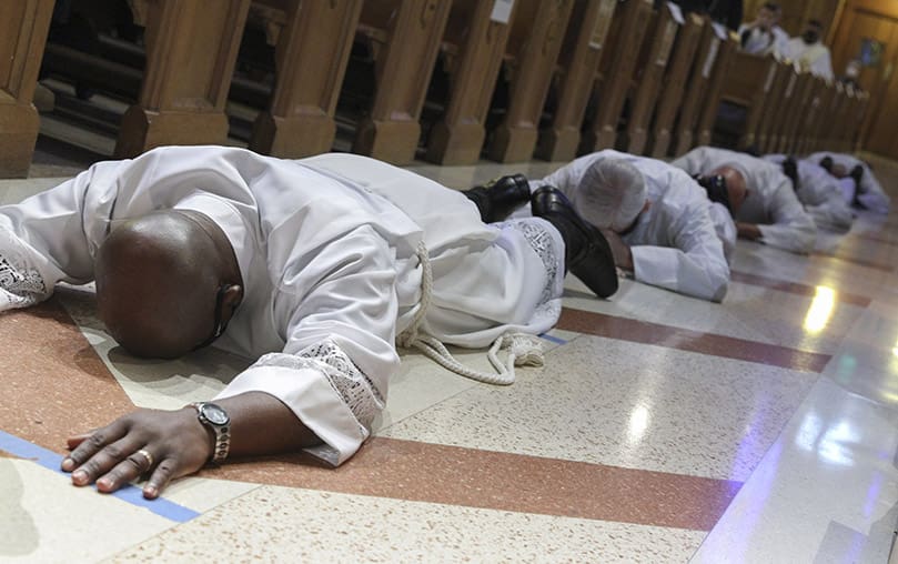 During the invitation to prayer, Dr. Henry Ohaya and five of his fellow permanent deacon ordination candidates lie prostrate in the center aisle at the Cathedral of Christ the King, Atlanta. They were ordained with Avery Daniel, a transitional deacon candidate. Photo By Michael Alexander