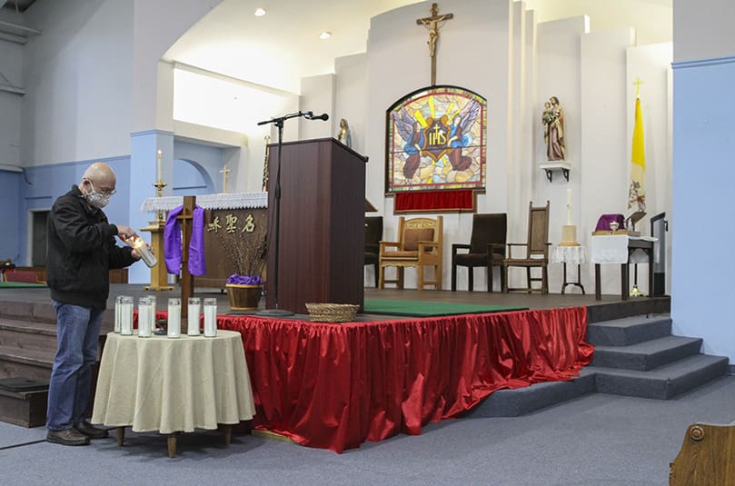 At the beginning of the 10:30 a.m. Mass, March 21, at Holy Name of Jesus Chinese Catholic Mission, Norcross, Andrew Shen, a native of Taiwan, lights one of the eight candles in remembrance of the eight victims killed in the March 16 mass shooting at three Atlanta-area massage parlors. Six of the eight victims were Asian. Photo By Michael Alexander