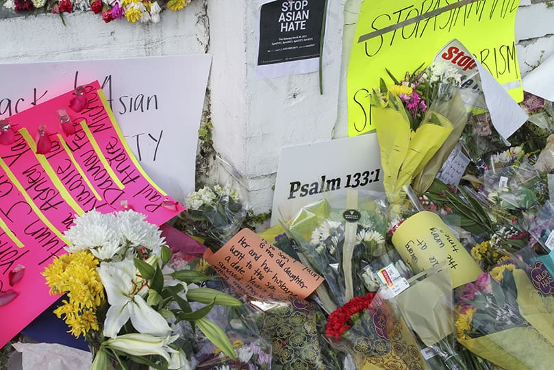 Among the flowers and notes displayed across the makeshift memorial at the Gold Spa, Atlanta, is a card printed with Psalm 133, verse one, on it. The psalm and verse states, “How good and how pleasant it is when God’s people live together in unity.” Photo By Michael Alexander