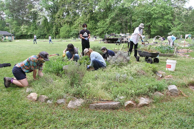 Flannery Pearson-Clarke, kneeling, far left, volunteer and outreach coordinator for Atlanta’s Food Well Alliance, works with some volunteers as they weed and clean out the herb garden section at the Stone Mountain Community Garden. Many of the volunteers working at the garden on April 17 signed up through the Food Well Alliance. The Stone Mountain Community Garden operates solely on the generosity of volunteers. There is no paid staff.