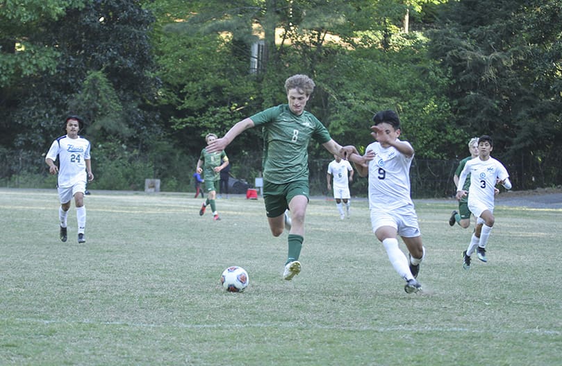 Holy Spirit Preparatory junior Dylan Delaney (#8) tries to keep Cristo Rey Atlanta’s Aaron Leal Reyes (#9) at bay, as he makes a play on the ball during the April 21 soccer match on the Holy Spirit campus. Freshman Timi Browne scored the winning goal to give Holy Spirit Preparatory a 2-1 victory over Cristo Rey. Photo By Michael Alexander