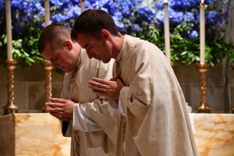 Atlanta's newest priests, Father Robbie Cotta, left, and Father Paul Nacey, right, bow during the solemn blessing at their ordination Mass June 12. Photo by Jackie Holcombe