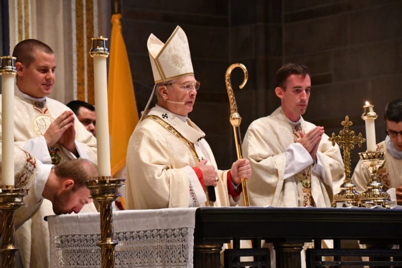 Archbishop Gregory J. Hartmayer, OFM Conv., flanked by newly ordained priests