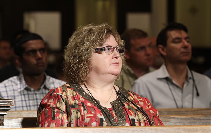 Morning sunlight passes through the stained glass windows on the south side of Sacred Heart of Jesus Basilica, Atlanta, as Linda Stepanek, the accounting and information technology manager for the Diocese of Rapid City, South Dakota, listens to the lector proclaim the first reading from second Book of Kings. She was among the more than 60 people on hand for the June 23 opening Mass of the Diocesan Information Systems Conference. Photo By Michael Alexander