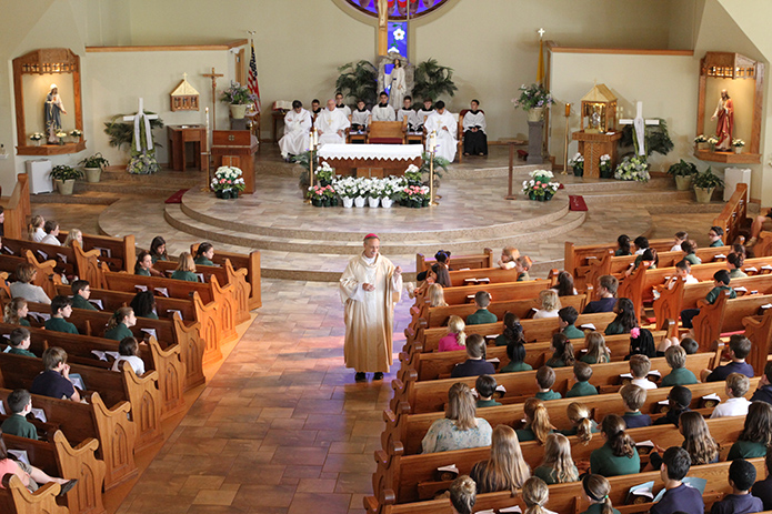 Bishop Luis Zarama, center aisle, was the main celebrant for the April 29 Mass at St. Catherine of Siena School, Kennesaw. Here he delivers a homily to the students based on the theme of Jesus’ words, “love one another,” from John’s Gospel. Photo By Michael Alexander