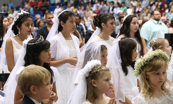 (L-r, back row) Jakeline Mendez, Ashley Sanchez, Melany Arrieta and Jennifer Lopez stand with their fellow first communicants during the Liturgy of the Eucharist at the May 1 Mass. Photo by Michael Alexander