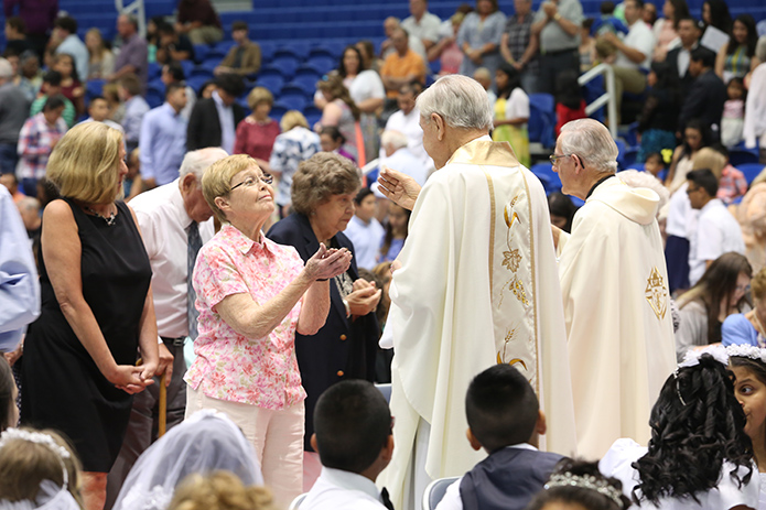 Father Richard Morrow, foreground, the founding pastor of Our Lady of Perpetual Help Church, Carrollton, was on hand for the special Mass at the University of West Georgia Coliseum. Here he helps distribute holy Communion with fellow senior priest Father John Kieran.
