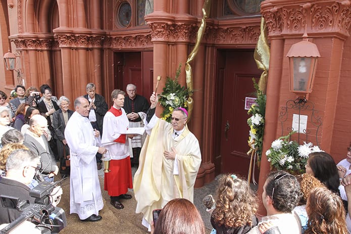 After sprinkling the Sacred Heart of Jesus Basilica’s Holy Door of Mercy with holy water, Bishop Luis Zarama turns and sprinkles the congregation. Photo by Michael Alexander