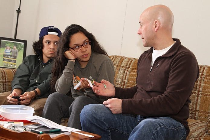 PJ Edwards, right, hands the name of a detainee to Jeniffer Salinas, 19, center, and Felix Amaya, 18, before their planned visit to the Stewart Detention Center, Lumpkin. Salinas’ family is from Mexico and Amaya’s family is from El Salvador. They are both students at Georgia Highlands College, and at one time both had a relative detained at the Stewart Detention Center. Photo By Michael Alexander