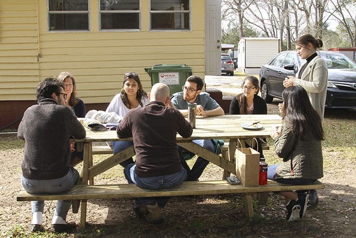 PJ Edwards, sitting, foreground center, conducts a debriefing session to inquire about the detainees and to hear about each person’s detention center visit experience. Gathering around the picnic table are (counter-clockwise from right) University of Georgia students Aileen Nicholas, Chandler Johnston, Blanca Lopez, Justin Payan, Mauli Desai, PJ’s wife Amy, and UGA student Giovanni Righi. Photo By Michael Alexander